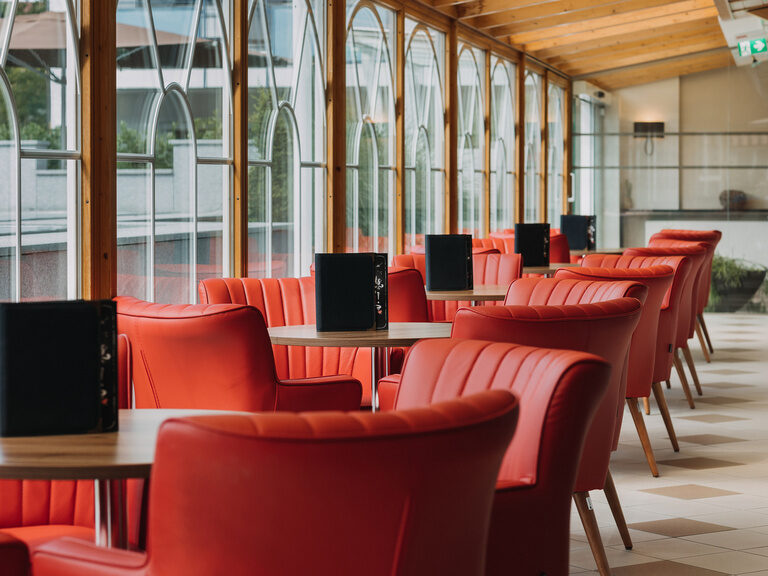 wintergarten-mit-roter-bestuhlung wintergarten-mit-gemuetlichen-zum-verweilen-einladenen-roten-stuehlen-fuer-kleine-snacks